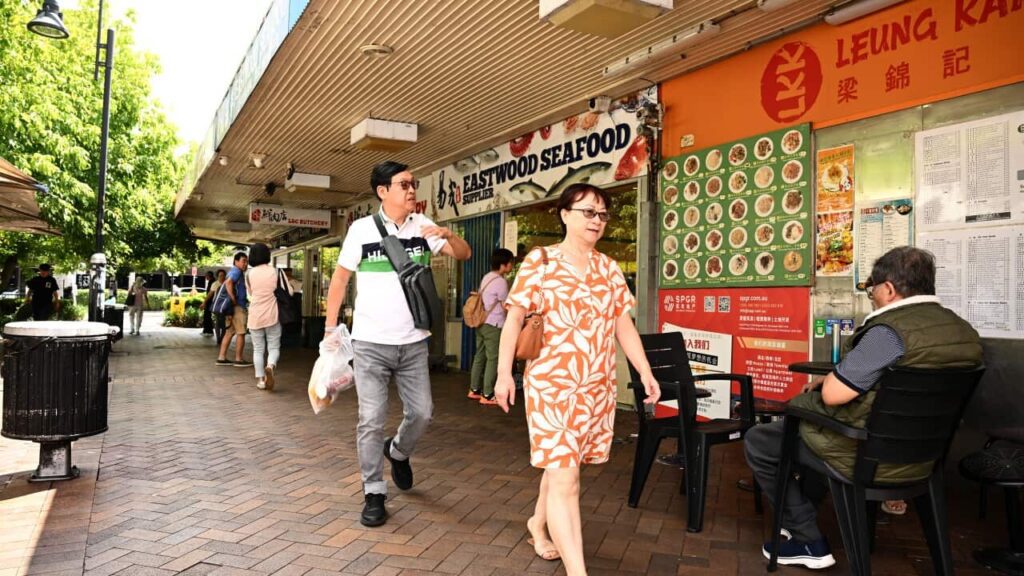 A man and a woman walk past restaurants and shops.